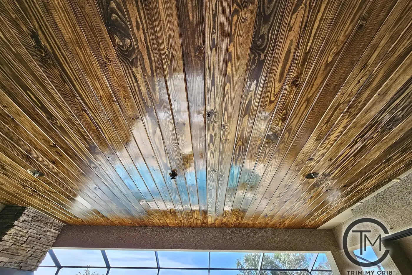 Looking straight up at an outdoor wood ceiling with bold grain and knots running toward the screen